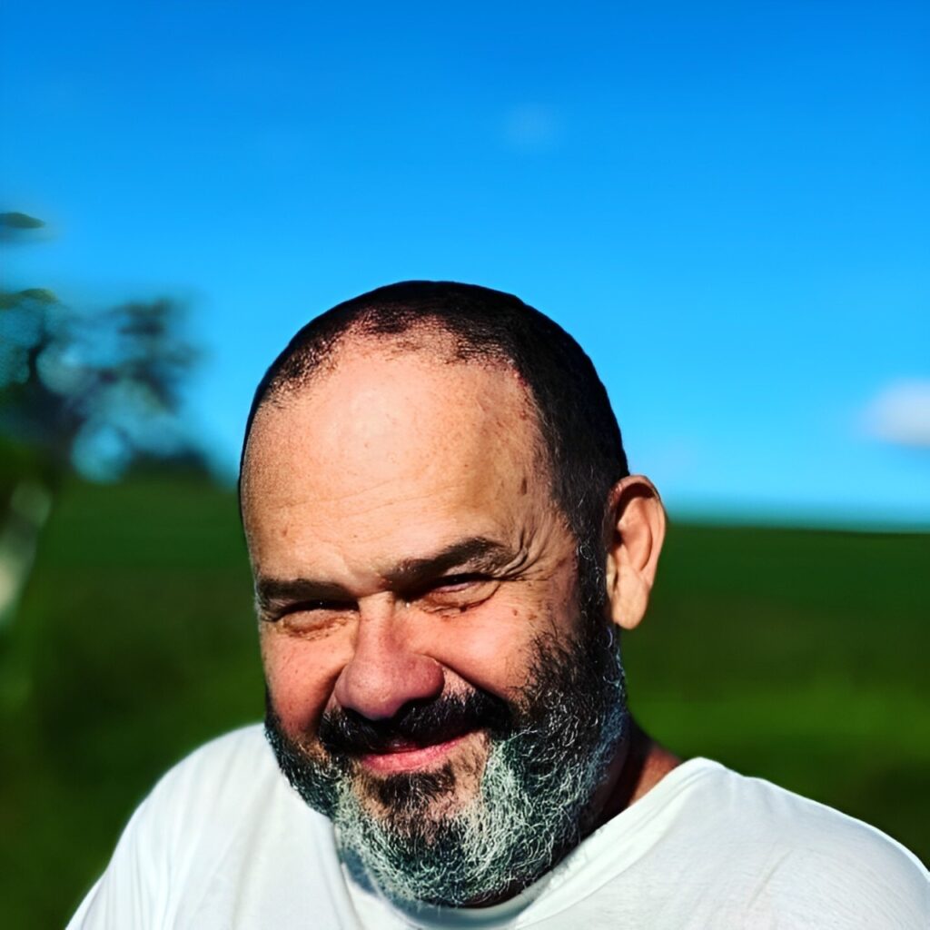 Eu, foto recente. Um pouco calvo, barba boa, mas começando a ficar grisalha no queixo abaixo do lábio, já está bem grisalha. Ao fundo o céu na Fazenda da minha cunhada no Paraná